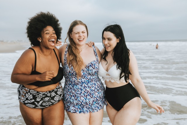 Cheerful plus size women enjoying the beach in their shapewear